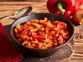 Schmor paprika mit Zwiebeln, ein Gericht, das man gut letscho selber machen kann. Serviert in einer Schüssel auf einem Holztisch.