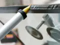 Applicator sprutar en tunn sträng av vätska längs en glaskant, som en del av en aquapel glasbehandling.