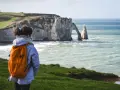 Une randonneuse admire les falaises d'Étretat, un paysage spectaculaire rappelant la beauté sauvage de la baie de Somme.