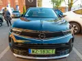 Czarny Opel z zieloną tablicą rejestracyjną WZ 183CT na tle innych samochodów.