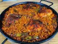Pyszna paella z kurczakiem, ryżem i warzywami w tradycyjnej patelni.