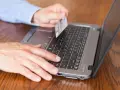 Mężczyzna z kartą płatniczą przy laptopie, szuka informacji jak sprawdzić blokady na koncie PeoPay.
