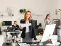 Kobiety w biurze, jedna trzyma dokumenty, druga rozmawia przez telefon.