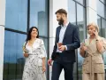 Mujeres con estilo para una conferencia: una con vestido estampado y clutch dorado, otra con traje de lino a rayas y hablando por teléfono.