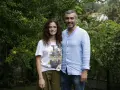 La forza di una donna puntata di oggi: una coppia sorride tra gli alberi. Lei indossa una maglietta con una bomba floreale, lui una camicia azzurra.