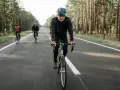 Cyclists on a road through a forest, likely engaged in a VO2 max training program, pushing their limits.