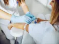 Pielęgniarka w rękawiczkach zakłada opaskę uciskową przed pobraniem krwi. Dowiedz się, gdzie zrobić badania krwi na NFZ.