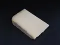 Un morceau de Cantal, lait cru ou pasteurisé, à la croûte rustique et à la pâte jaune pâle, posé sur un fond sombre.