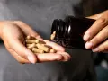 Hände schütten Kapseln aus einer braunen Flasche. Die Kapseln liegen in der Handfläche, bereit zur Einnahme. Möglicherweise zur Unterstützung der chrom wirkung.