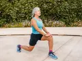 Femme âgée faisant un étirement des jambes, préparation pour un échauffement pieds randonnée.