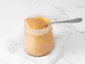 Un tarro de manjar blanco cremoso, listo para ser disfrutado con una cuchara.