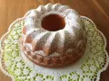Ein goldbrauner Quark Gugelhupf, bestäubt mit Puderzucker, auf einer zarten Spitzendeckchen.