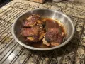 Succulente cosce di pollo in padella, dorate e saporite, riposano su una griglia.