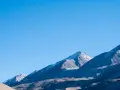 Sullo sfondo di montagne innevate, un cielo azzurro limpido è punteggiato da forme sinchisi scintillante, come piccoli puntini e curve sinuose.