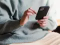 Dłonie trzymające telefon, zastanawiające się, co napisać po kłótni.