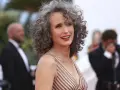 Mujer sonríe con modernos cortes de pelo con canas, luciendo un vestido a rayas.