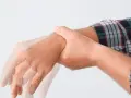 Dłoń mężczyzny w koszuli w kratę z widocznym drżeniem.