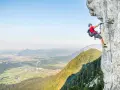 Ein Mann klettert gesichert an einem Stahlseil einen Felsgrat entlang. Ein Abenteuer auf einem der vielen Klettersteige Deutschlands.