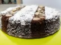 Torta caprese ricetta originale napoletana, soffice e scura, cosparsa di zucchero a velo e mandorle a lamelle.