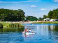 Rodzina na rowerku wodnym na jeziorze, plaża pełna ludzi, las i budynki w tle. Idealne miejsce gdzie nad wodę Dolny Śląsk.