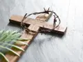 Holzkreuz mit Dornenkrone und Palmblatt. Christen fasten Regeln, um sich auf Ostern vorzubereiten.