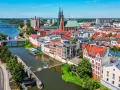 Widok na Odrę i zabytkowe centrum Opola. Rzeka, mosty, kościół i kamienice tworzą malowniczy krajobraz, idealny do odkrywania opolskich atrakcji.