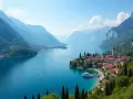 Malownicze miasteczko nad jeziorem Como lub Garda, z górami w tle i łodziami na turkusowej wodzie.