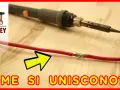Un saldatore pronto a collegare fili elettrici, con un cavo rosso già unito.