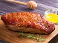 Un magret de canard au barbecue, la peau dorée et croustillante, prêt à être dégusté avec une touche de miel et de thym.