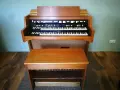 Ein schönes Hammond-Musikinstrument mit zwei Manualen und einer Holzbank davor.