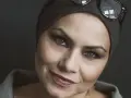 Sylwia Janowicz-Dobrowolska w szarej opasce i okularach na głowie, z wyrazistym makijażem oczu i błyszczącymi ustami.