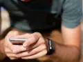 Mężczyzna trzyma smartfon, a na jego nadgarstku widać smartwatch. Właśnie sprawdza, jak sparować zegarek z telefonem.