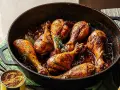 Sabroso pollo a la cerveza dorado y jugoso, cocinado en una sartén de hierro fundido con hierbas aromáticas.