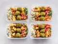 Vier Behälter mit gesunden meal prep Rezepten: Reis, Falafel, geröstetes Gemüse und Salat.