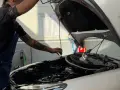 Meccanico con tatuaggi controlla il motore. Capire la differenza tra tagliando e revisione è fondamentale per la manutenzione dell'auto.