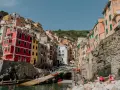 Colorful buildings cling to a hillside overlooking a harbor, a picturesque scene after a train from Bologna to Cinque Terre.