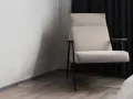 Fauteuil moderne avec un élégant tissu assise chaise, pieds fins et accoudoirs en bois. Il est placé près d'un mur blanc et de rideaux sombres.
