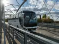 Biały autokar PKS NOVA jedzie przez most, pokonując trasę Warszawa-Augustów.