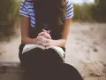 Kobieta z dłońmi złożonymi nad otwartą Biblią. To jej modlitwa o dobry dzień w pracy.