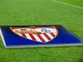 Herb Sevilla FC na tle murawy. Gotowość do kolejnych rozgrywek.
