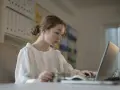 Młoda kobieta uczy się, jak zostać księgowym bez studiów, korzystając z laptopa i karty.