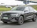 Czarny Audi Q8 e-tron sunie po drodze. Zastanawiasz się nad audi q8 cena? Ten luksusowy SUV coupe robi wrażenie.