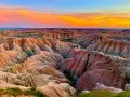 Un paisaje desértico con formaciones rocosas erosionadas, **las carcavas**, bajo un cielo anaranjado y azul al atardecer.