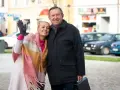 Małgorzata Szeptycka wita się z uśmiechem, obejmując partnera. W tle miejski krajobraz z samochodami.