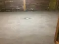 Nybehandlad betongskiva med golvbrunn i mitten. Väggarna är av trä och synliga rör och isolering.