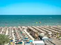 Słoneczna plaża w Rumunii, pełna leżaków i parasoli. Ludzie kąpią się w morzu, idealne miejsce na wakacje.
