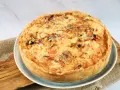 Eine goldbraune Sommer Quiche mit geschmolzenem Käse und bunten Gemüsestückchen, bereit zum Genießen.