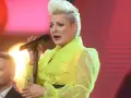 Wokalistka w neonowej kreacji śpiewa canzone d'amore, a obok niej mężczyzna z uśmiechem na twarzy.