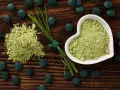 Zielony proszek i tabletki na drewnianym tle. Dowiedz się, spirulina co to za superfood!