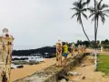 Kobieta przytula zardzewiały słup na plaży, wspominając dawne czasy na Wyspach Tomasza.